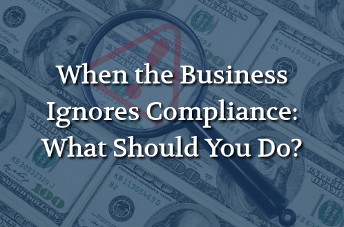 Magnifying glass highlighting a warning symbol over U.S. currency, representing business compliance risks and financial consequences.