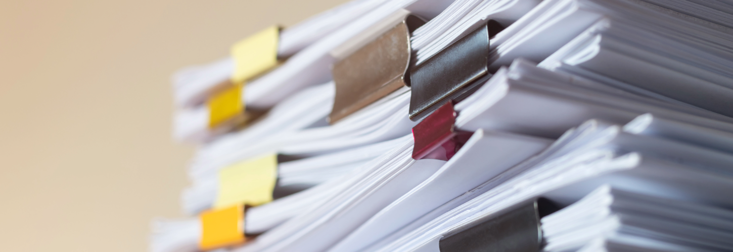 Close-up of stacked investigation documents secured with binder clips, representing case files, evidence documentation, record management, and compliance investigations.