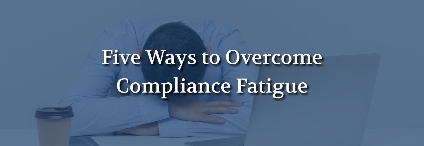 Fatigued professional resting their head on folded arms beside a laptop, illustrating workplace compliance fatigue.